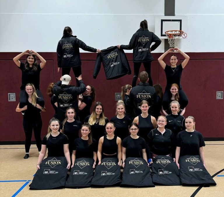 Gruppenshooting eines Cheerleading-Teams in sportlicher Kleidung, einige Mitglieder posieren gestapelt.