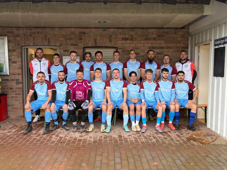 Mannschaftsbild einer Fußballmannschaft in blauen und roten Trikots, sitzend und stehend.